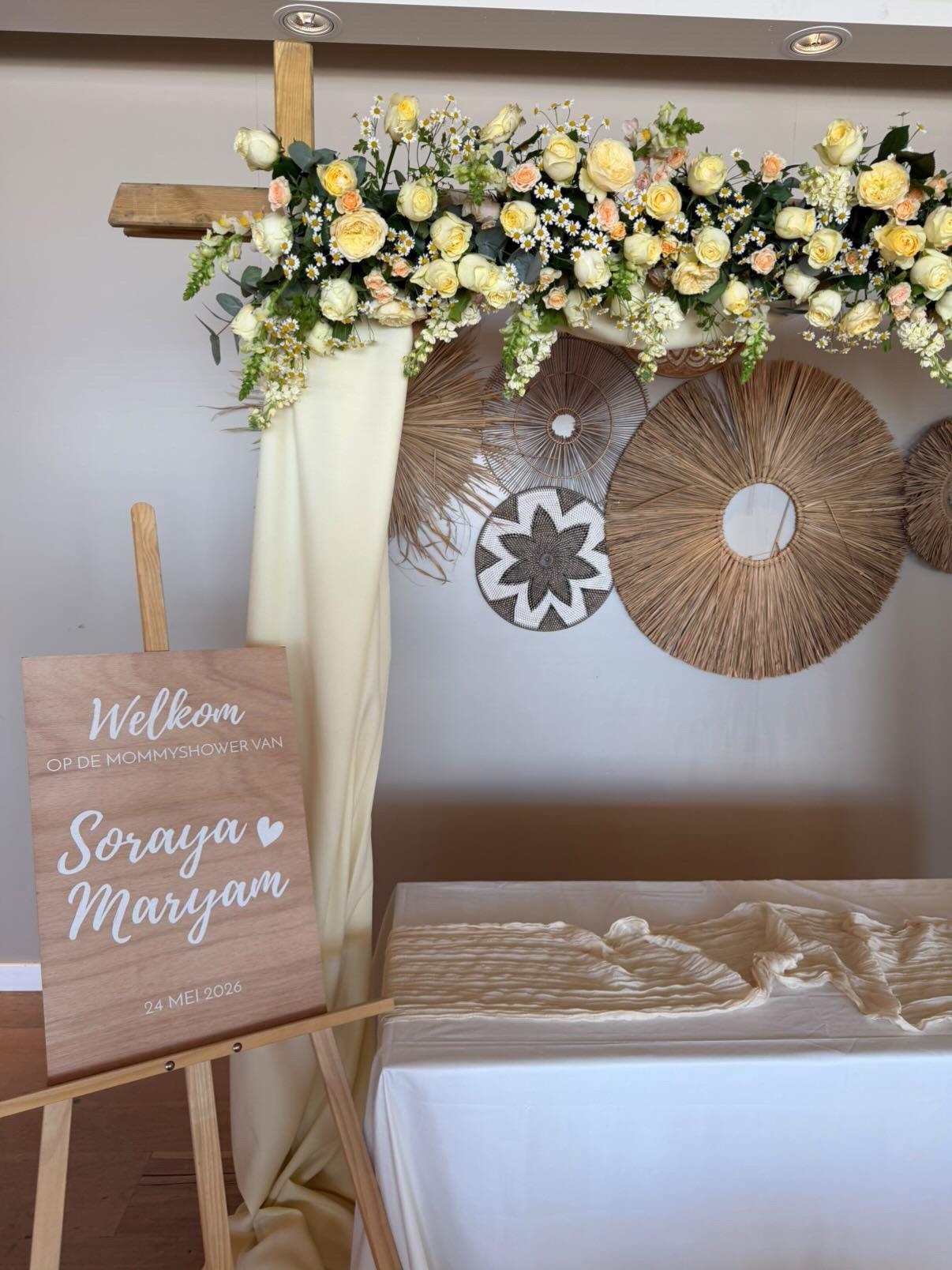 Houten welkomstbord met bloemen en rieten wanddecoratie op de achtergrond