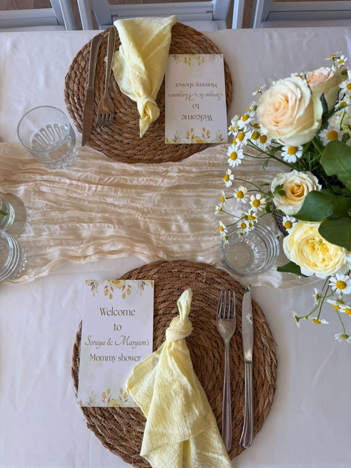 Van bovenaf gefotografeerd couvert met rieten placemat, gele servetten en welkomstkaart