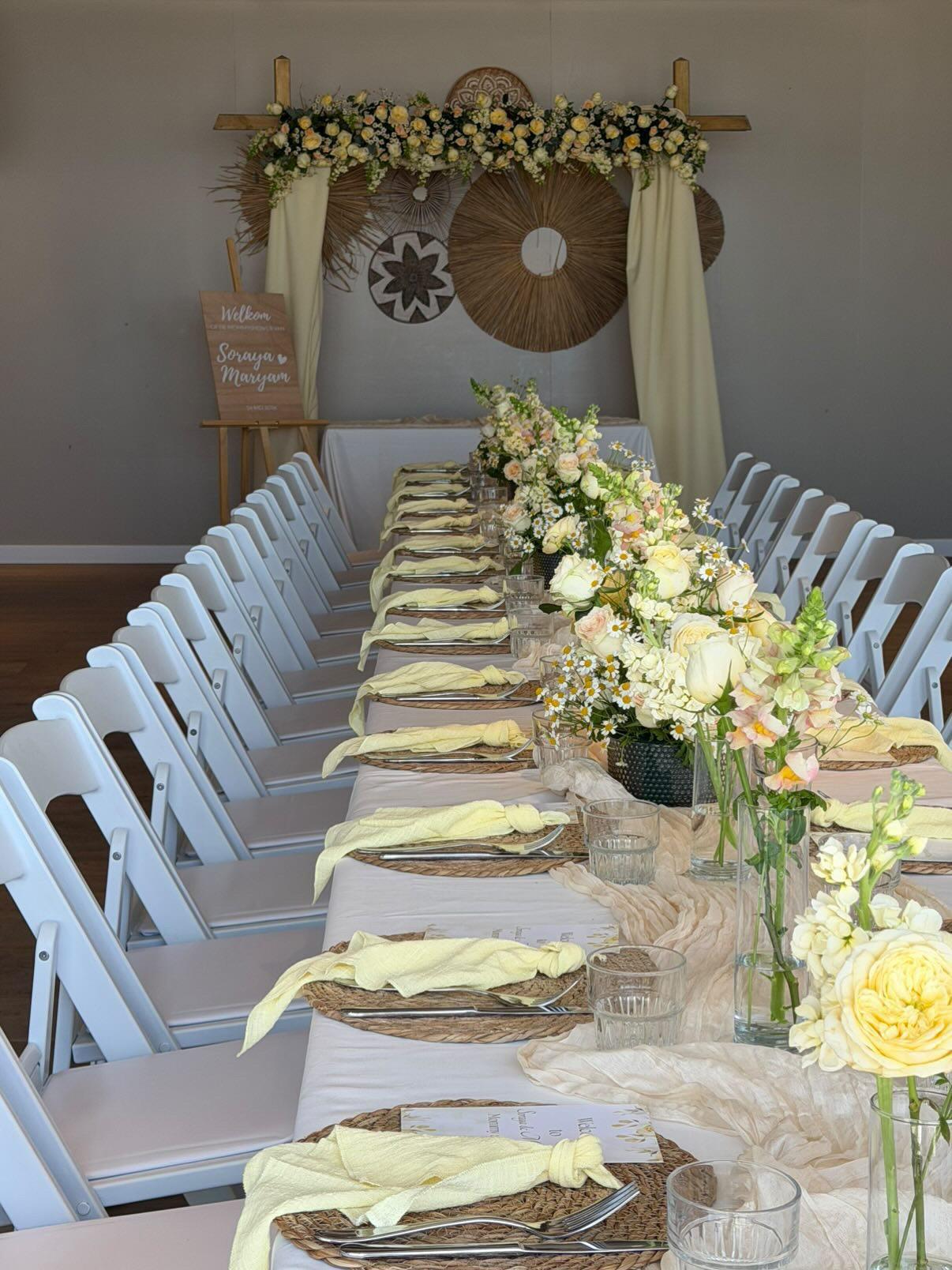 Lange gedekte tafel met bloemenboog tijdens een babyshower aan zee bij Zeezicht